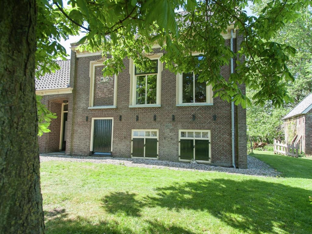 una casa de ladrillo con un árbol delante de ella en Charming house in Easterlittens on a Frisian farm, en Wommels