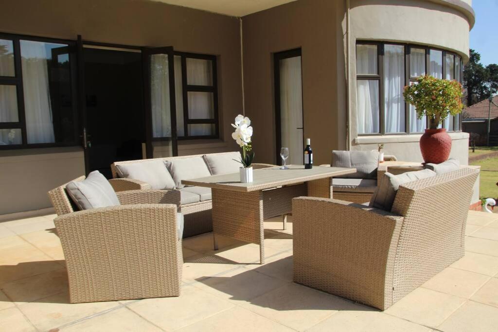 a patio with wicker furniture and a table and chairs at Beautiful Home in Houghton in Johannesburg