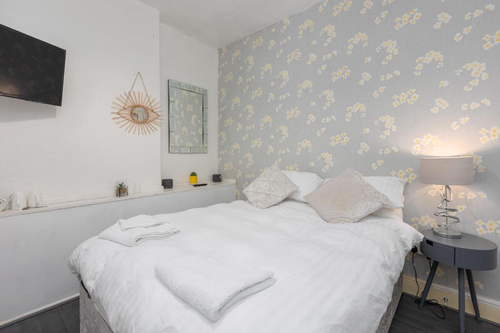 a bedroom with a white bed with yellow flowers on the wall at The B & B Blackpool in Blackpool