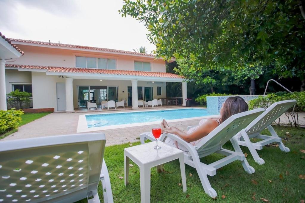 una mujer sentada en una silla de césped con una copa de vino en Impresionante villa con piscina Metro Country Club, en Paraíso
