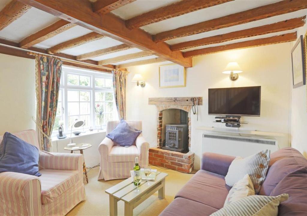 uma sala de estar com um sofá e uma lareira em Rose Cottage em Bealings