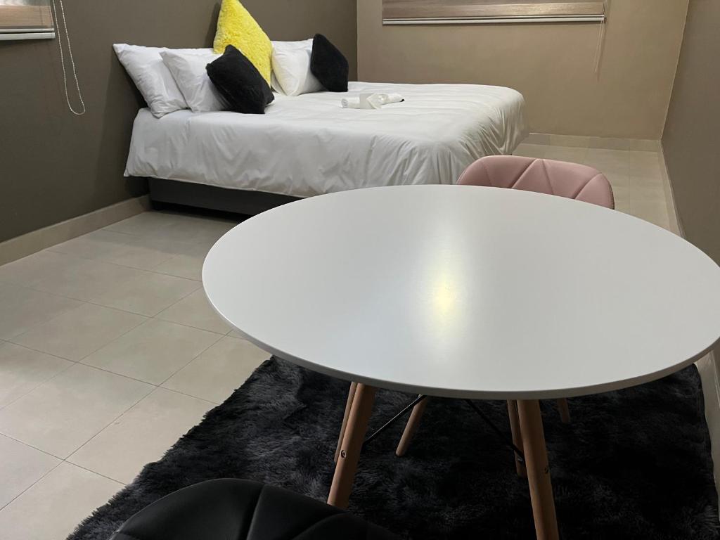 Maponya Guest House في Pimville: طاولة بيضاء وكراسي في غرفة بها سرير