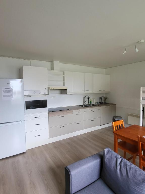 uma cozinha com armários brancos, uma mesa e um sofá em Vollvaagen Apartments Smøla, boat included em Smøla