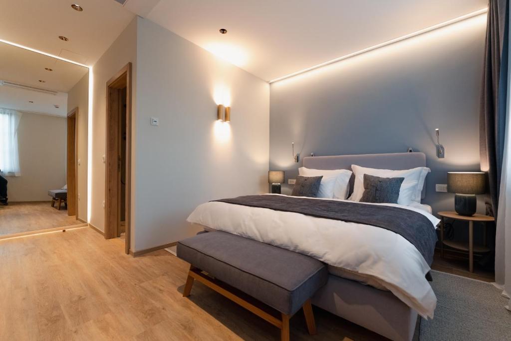 a large white bedroom with a large bed and a bench at Vila De Casa in Ribnica