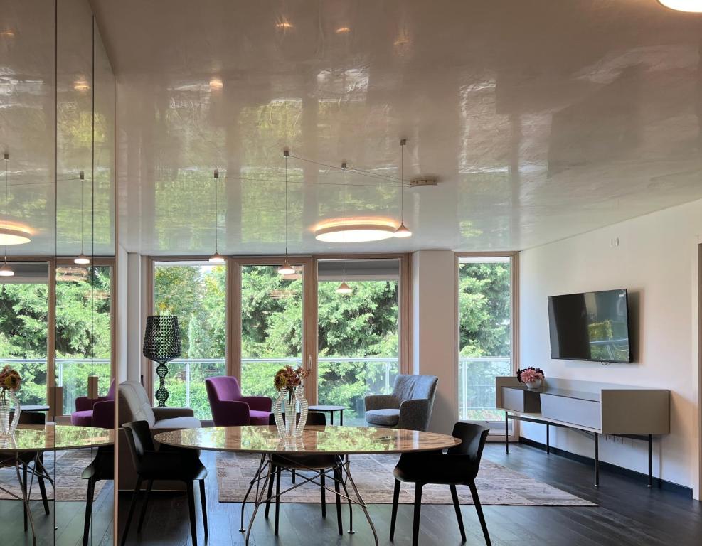 ein Esszimmer mit einem Tisch, Stühlen und Fenstern in der Unterkunft Grand Apartment Sissi in Triest