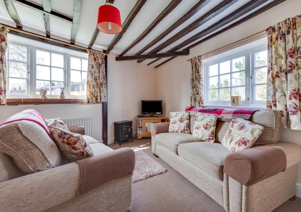 a living room with two couches and windows at Corner Cottage in Wangford