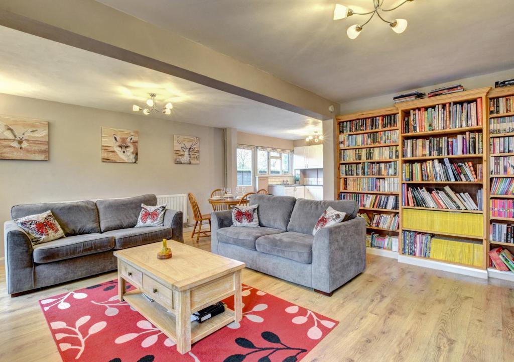 a living room with two couches and bookshelves at Barn Owl Retreat Sibton in Sibton
