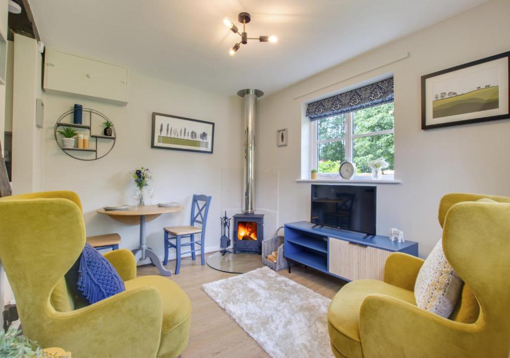 a living room with yellow chairs and a fireplace at Perch Place in Kettleburgh