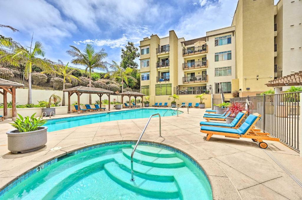 a swimming pool with chairs and a building at Breezy Oceanside Condo Less Than half Mi to Beach! in Oceanside