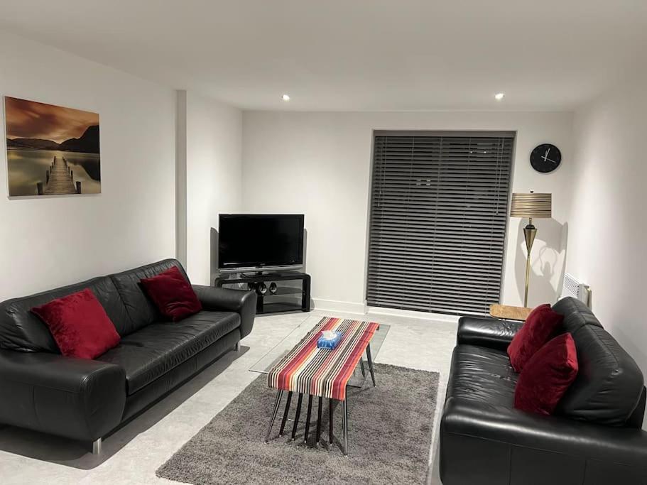 a living room with black leather furniture and a flat screen tv at Orion building apartments ,OPOSITE GRAND CENTRAL,FREE CAR PARK in Birmingham