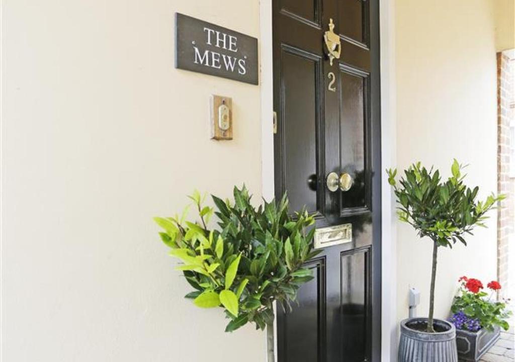 a black door with plants and a sign on it at The Mews in Southwold