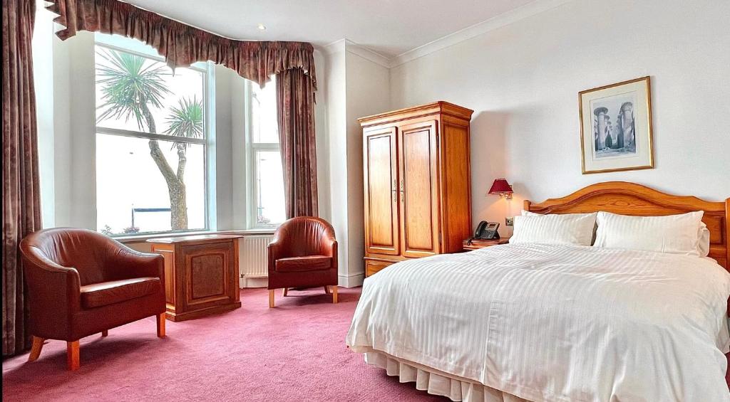 1 dormitorio con 1 cama, 2 sillas y ventana en Promenade House en Douglas