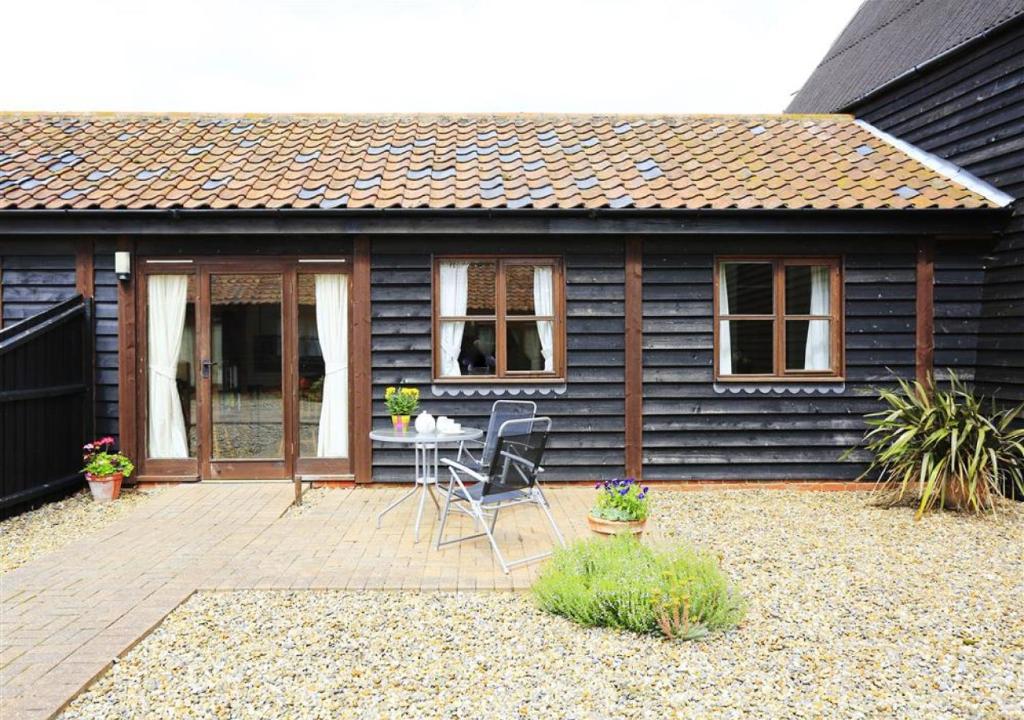 a small house with a patio with a table and chairs at The Tack Room in Wangford