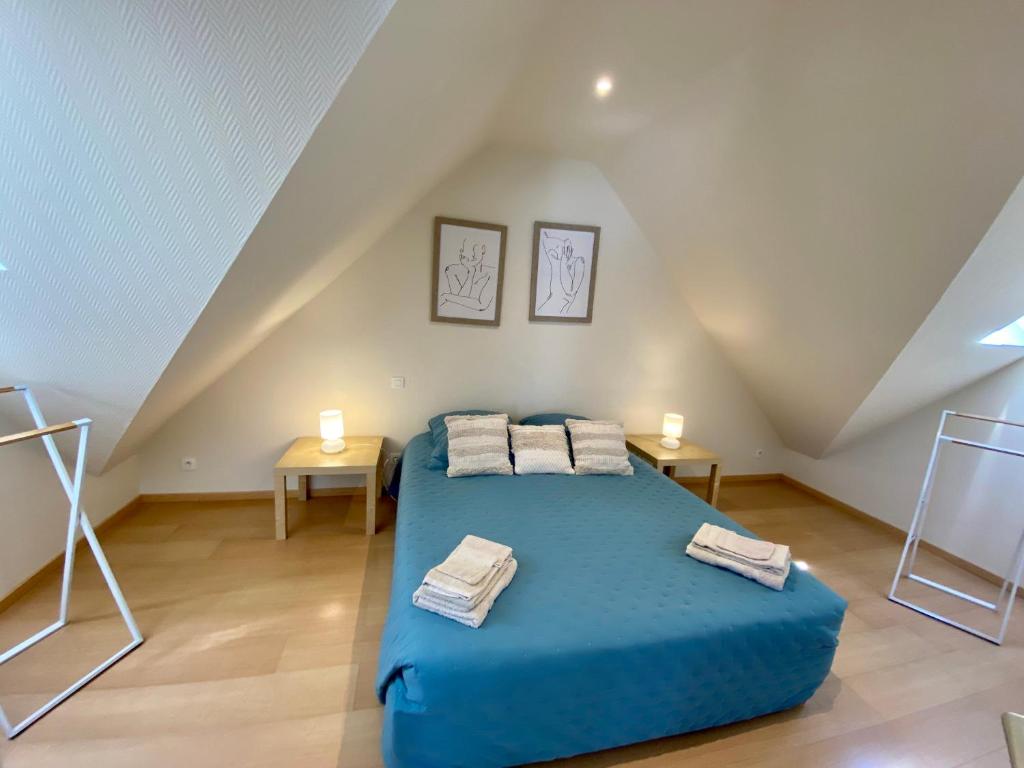 a bedroom with a blue bed in a attic at Résidence De La Rance in La Richardais