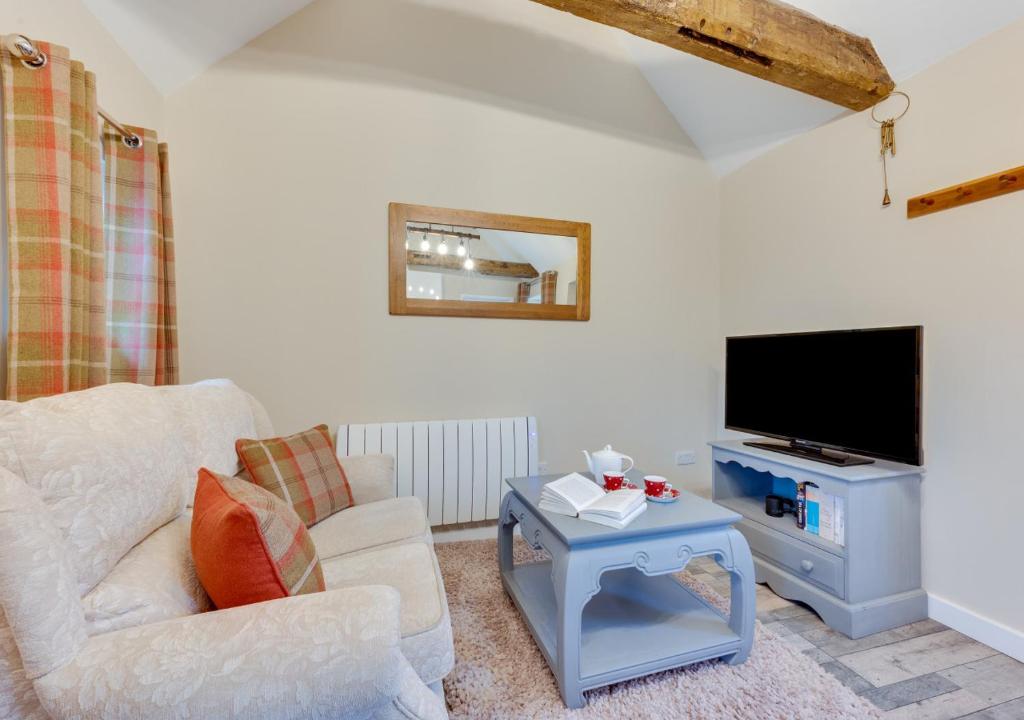uma sala de estar com um sofá, uma televisão e uma mesa em Ardley Cottage Hedgehog em Waldingfield
