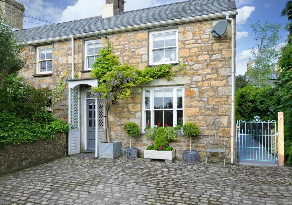 a stone house with a gate and plants in front of it at 2 Bryn Hyfryd in Llanbedrog