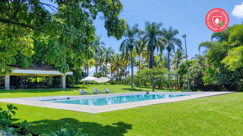 a swimming pool in a park with palm trees at Rancho La Joya in Xochitepec