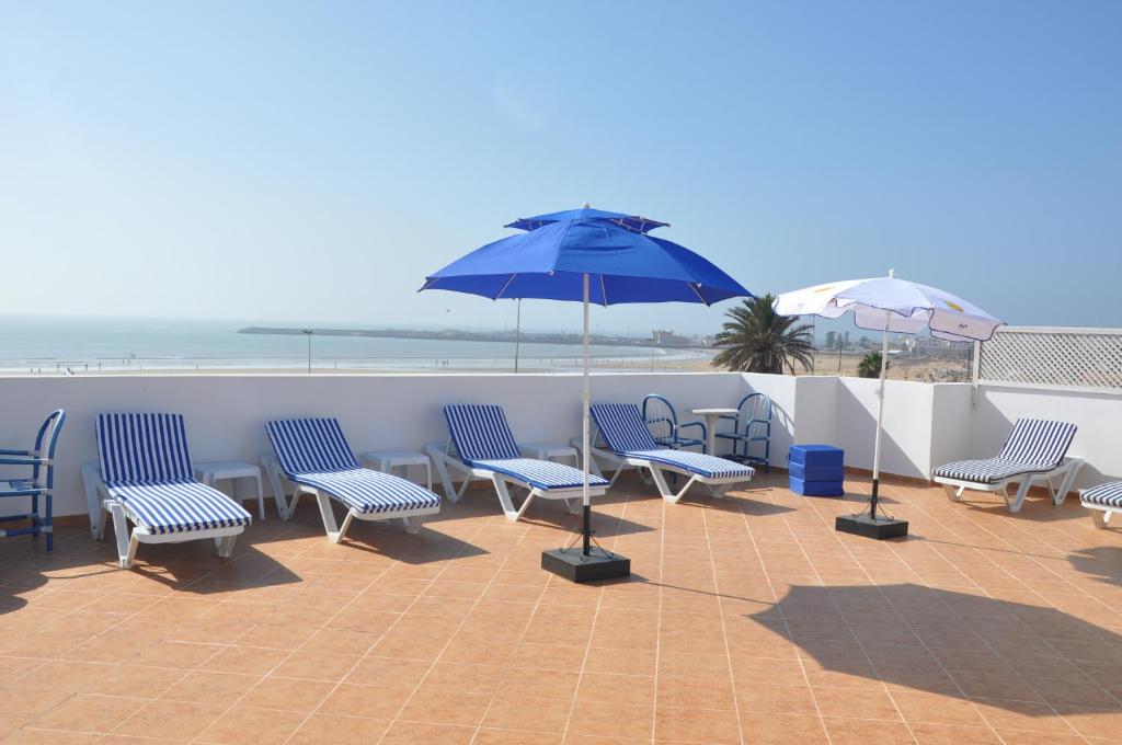 een groep stoelen en een parasol op een patio bij Résidence La Galiote in Essaouira