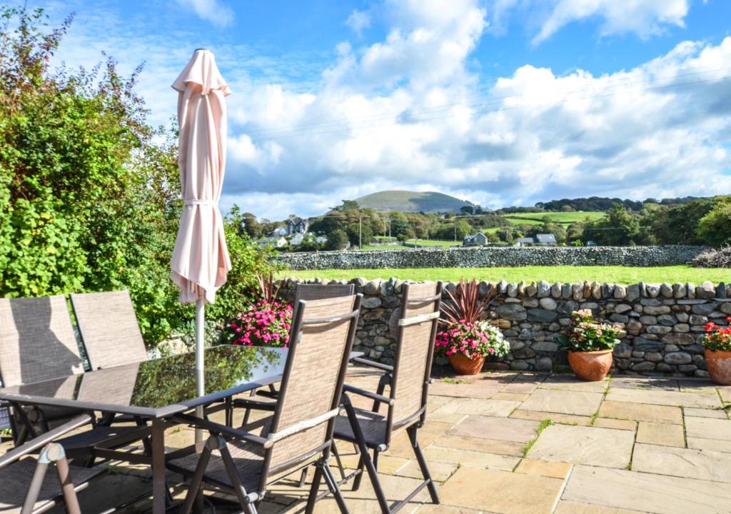 a patio with a table and chairs and an umbrella at 3 Tyn Llan in Dyffryn