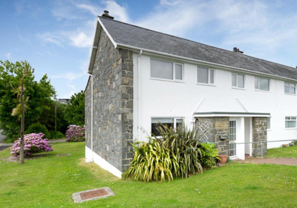 a large white house with a grass yard at 45 Cae Du in Abersoch