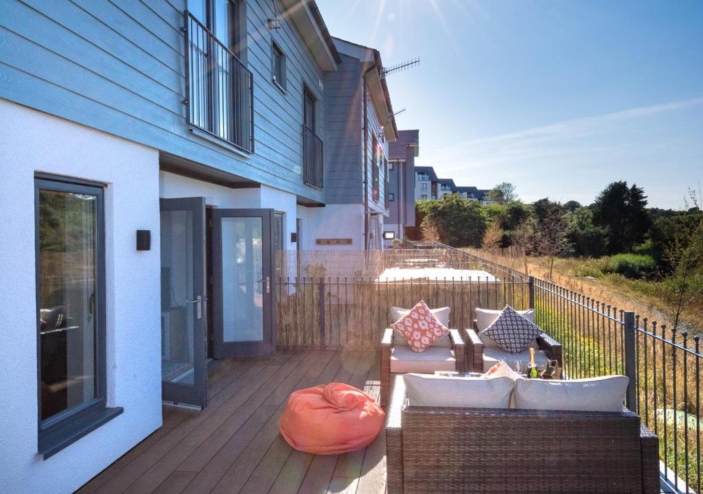 a deck with a couch and chairs on a house at 7 Pen y Bont in Abersoch