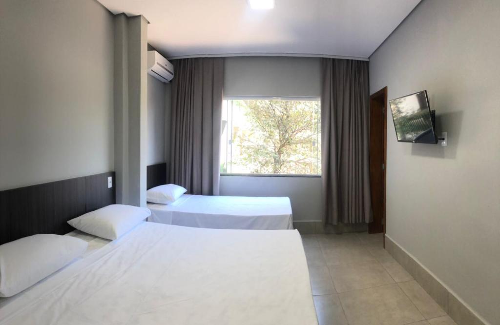 a hotel room with two beds and a window at Vila Nóbrega Residencial in Foz do Iguaçu