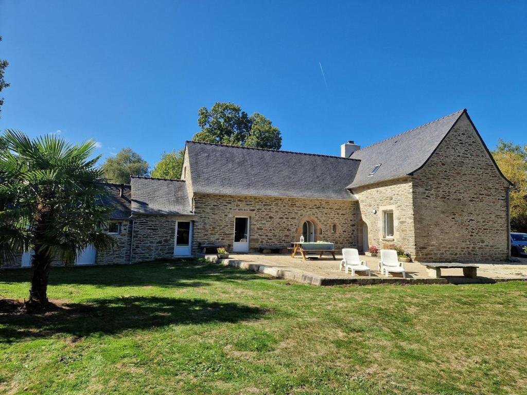 ein großes Steingebäude mit zwei Stühlen und einem Tisch in der Unterkunft Holiday Home Plouégat-Guérand - BRE05042-F in Plouégat-Guérand