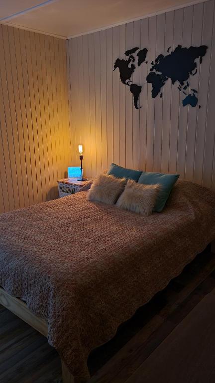 1 dormitorio con 1 cama con mapa en la pared en Wanderlust Monoambiente Ushuaia en Ushuaia