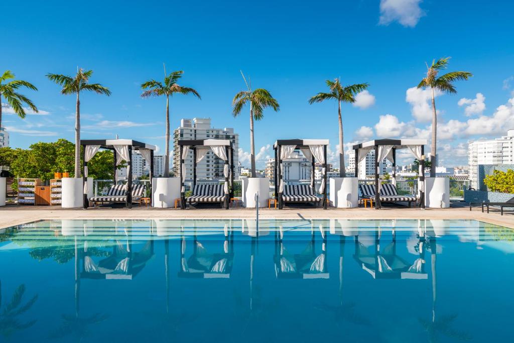 uma piscina com cadeiras e palmeiras num edifício em Boulan South Beach em Miami Beach