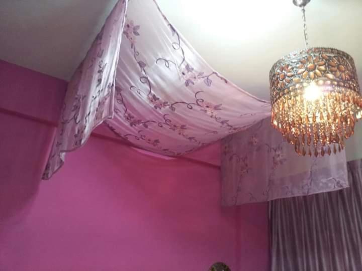 a pink room with a chandelier and a pink wall at Hualien Seaside B&amp;B in Hualien City