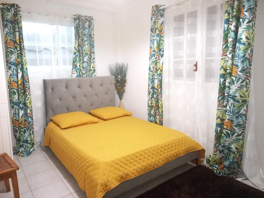 sypialnia z łóżkiem z żółtą pościelą i zasłonami w obiekcie Charmant logement avec spa/petit-déjeuner inclus. w mieście Pointe-Noire