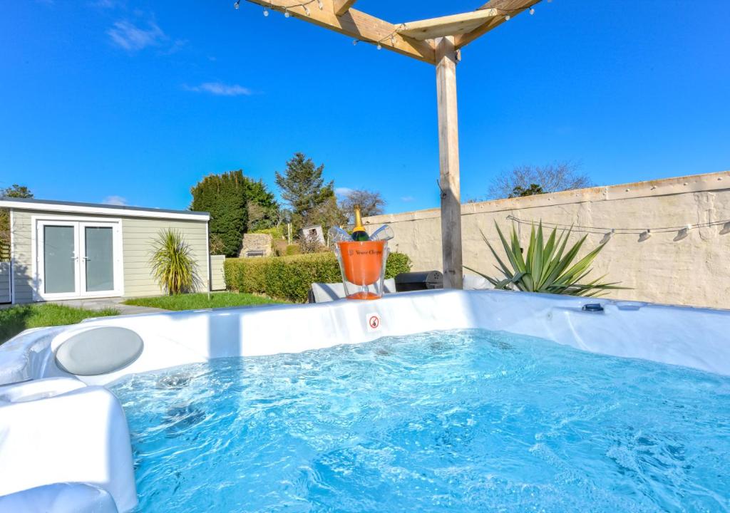 a hot tub in a backyard with a house at Bryn Tirion in Llanbedrog