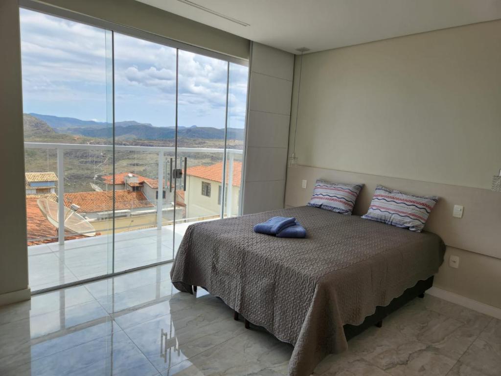 a bedroom with a bed and a large window at Apto inteiro de luxo em Diamantina in Diamantina