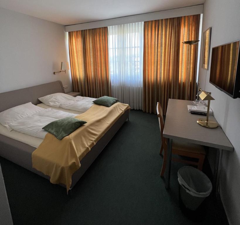 een hotelkamer met een bed, een bureau en een tafel bij Hotel Exquisit in Minden