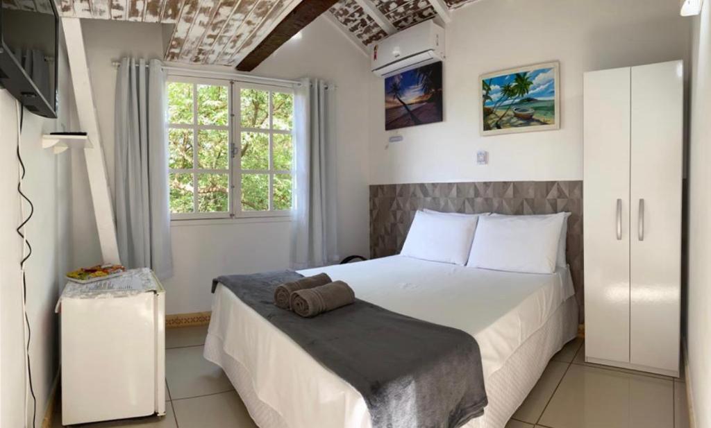 a bedroom with a white bed and a window at Recanto da Ferradura in Búzios