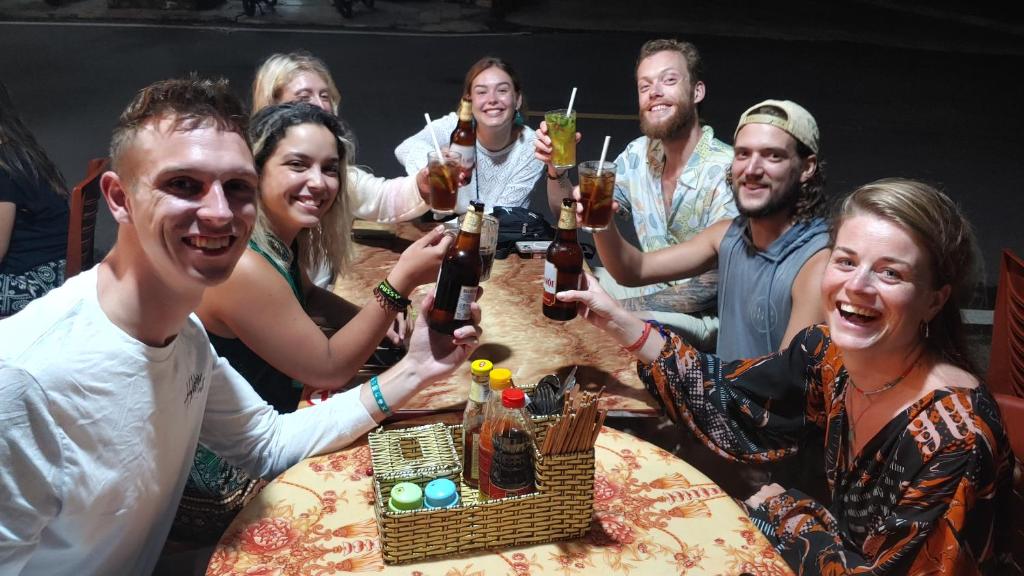 un grupo de personas sentadas alrededor de una mesa con bebidas en Luna's House Hostel en Cat Ba