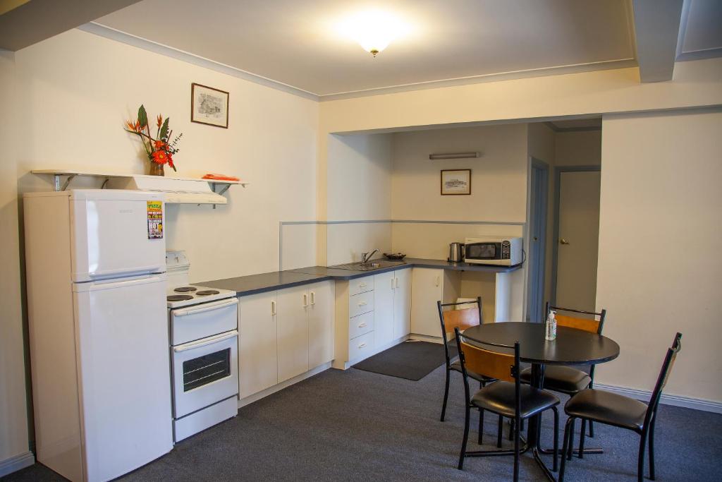 een keuken met een tafel en een witte koelkast bij Cherry Lane Apartments in Bright