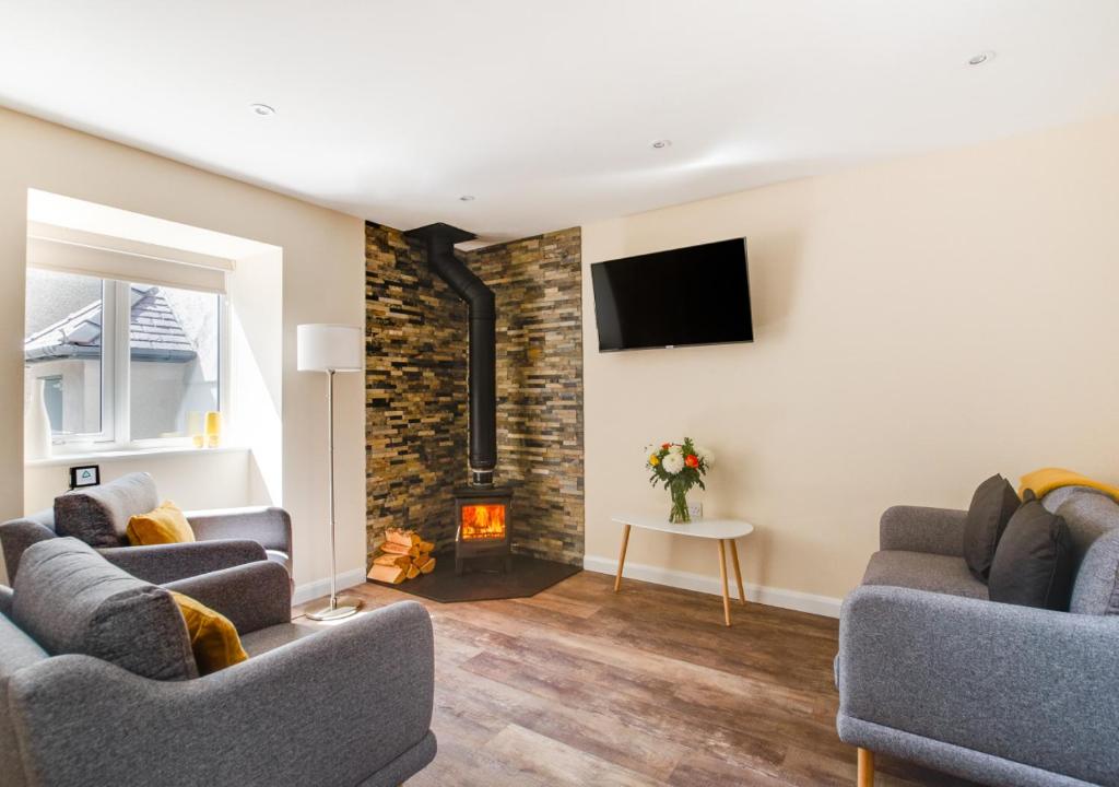 a living room with two couches and a fireplace at Bwthyn Clyd in Llanddyfnan