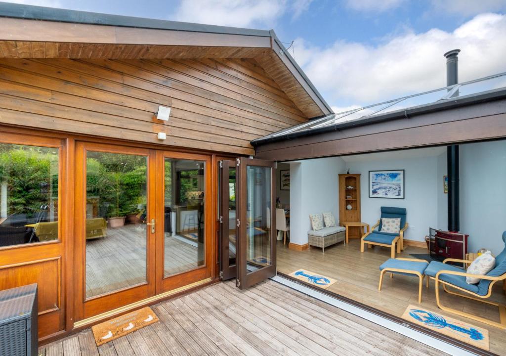 a house with a large deck with sliding glass doors at Cascade in Saundersfoot