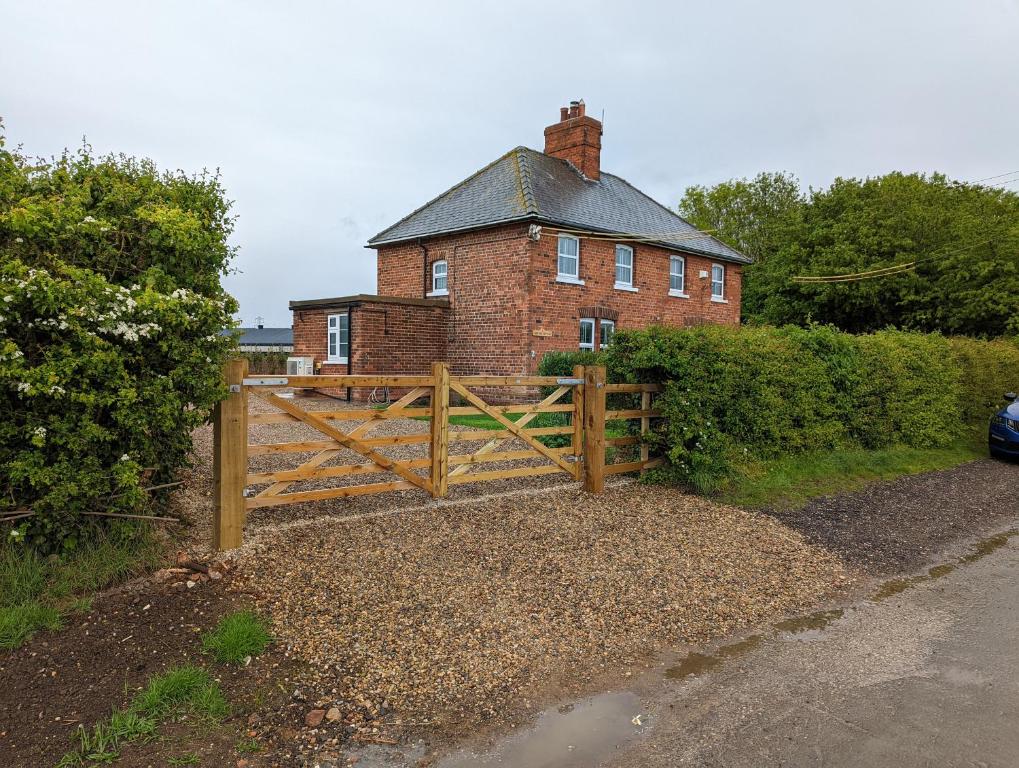 un cancello di legno davanti a una casa di mattoni di 2 Lane End Cottages a Hull