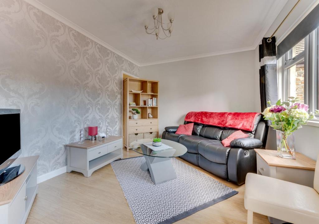 a living room with a couch and a tv at Cheries Place in Amroth