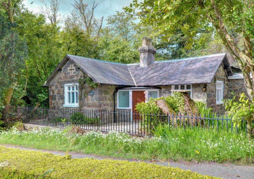 an old stone house with a fence in front of it at The Lodge in Pwllheli