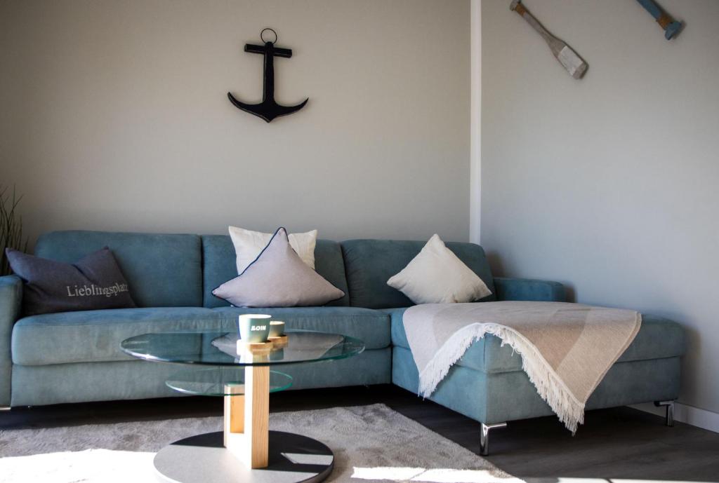 a living room with a blue couch and a glass table at Ferienhaus "Q" - Wohnung 3 in Zingst