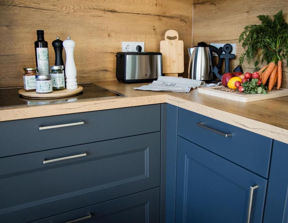 a kitchen counter with blue cabinets and fruits and vegetables at Ferienhaus "Q" - Wohnung 4 in Zingst