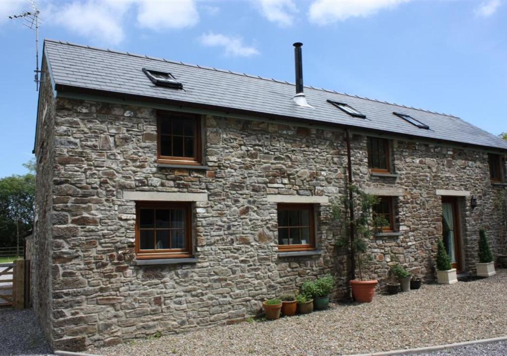 una casa de piedra con ventanas y macetas en Maggies Cottage, en Begelly