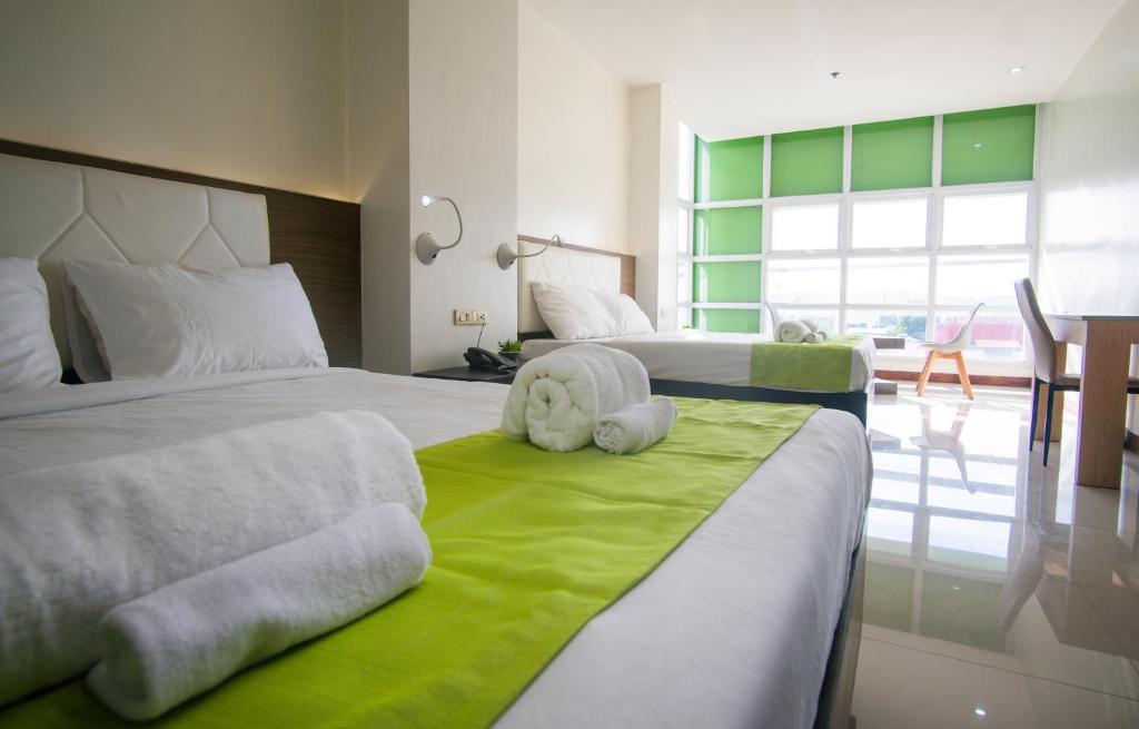 um quarto com 2 camas e toalhas num cobertor verde em Benrose Hotel em Cagayan de Oro