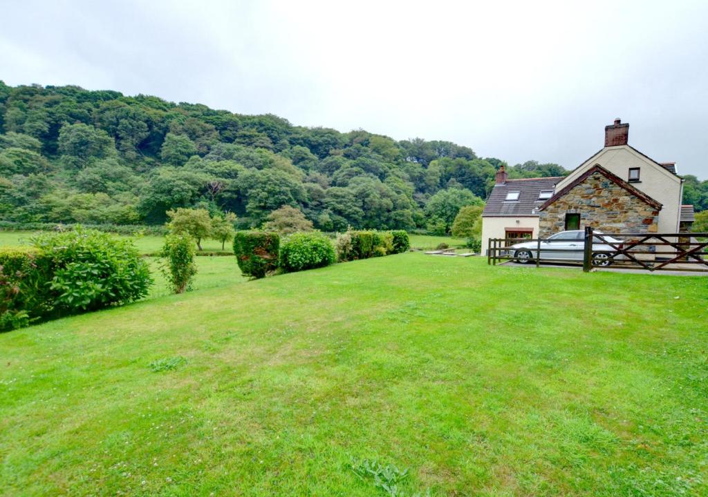 a large yard with a house and a grass field at Llysyfelin in Pontfaen