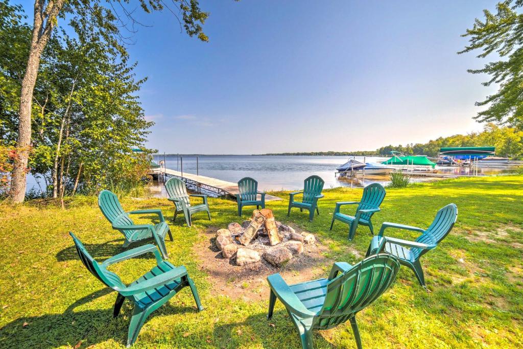 a group of lawn chairs sitting around a fire pit at Crivitz Lakefront Escape with Boat Dock and Slip! in Crivitz