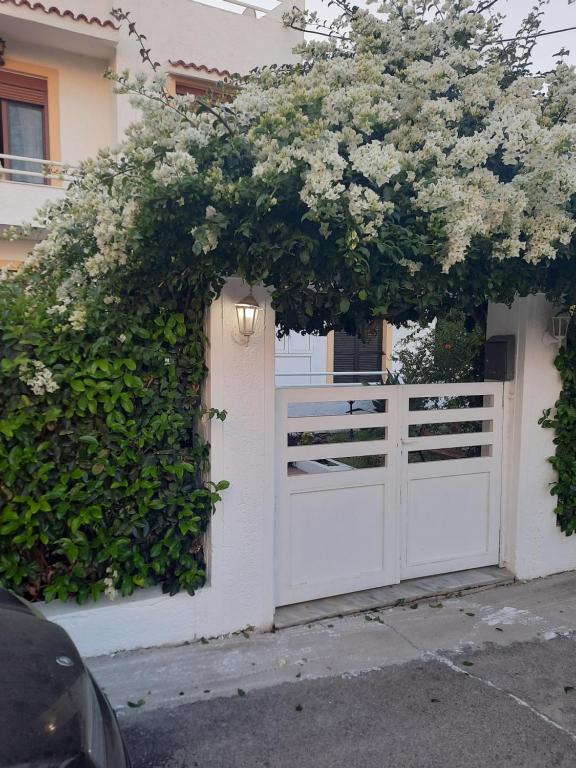 a white fence with a white gate with flowers on it at Villa Bianca in Kremasti