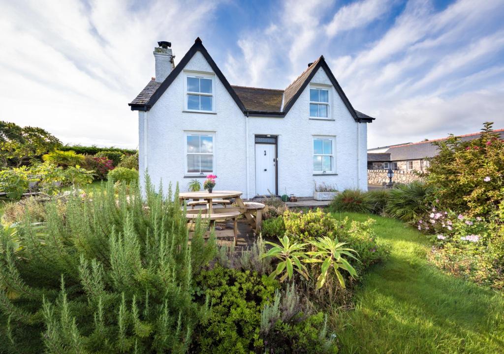 a white house with a table in a garden at Tyddyn Talgoch Isaf in Abersoch